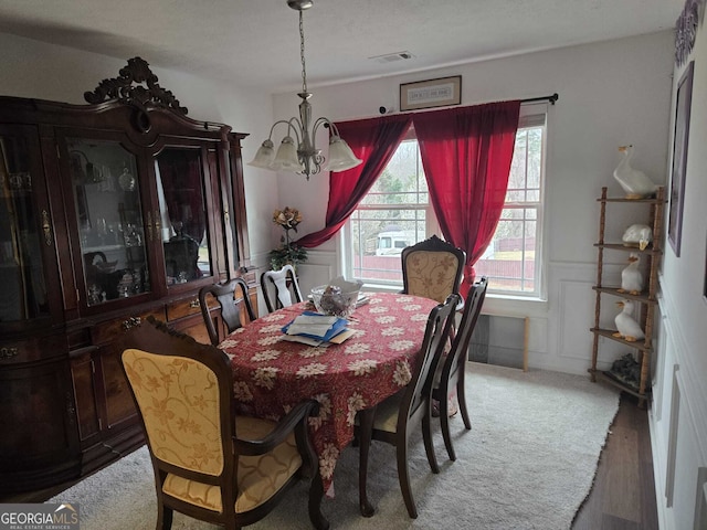 dining room featuring visible vents, a wainscoted wall, an inviting chandelier, and a decorative wall