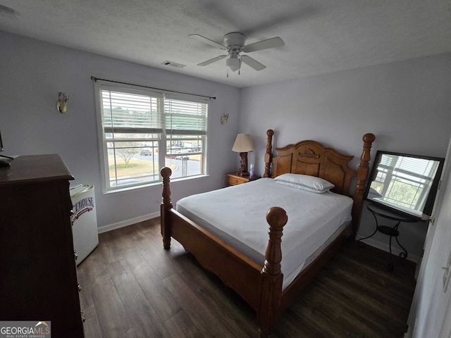 bedroom with visible vents, ceiling fan, baseboards, wood finished floors, and a textured ceiling