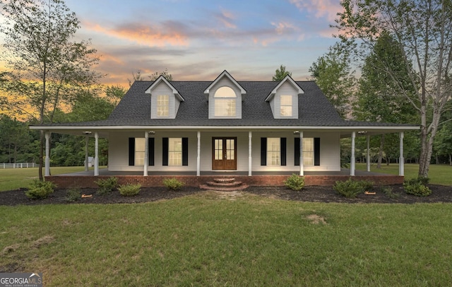 farmhouse featuring a yard, a porch, and roof with shingles