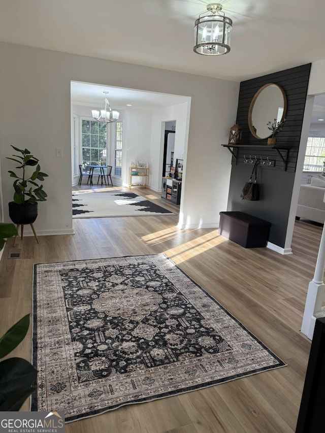 corridor with baseboards, wood finished floors, visible vents, and a notable chandelier