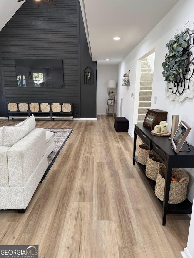 living room with light wood-type flooring, recessed lighting, baseboards, and stairs