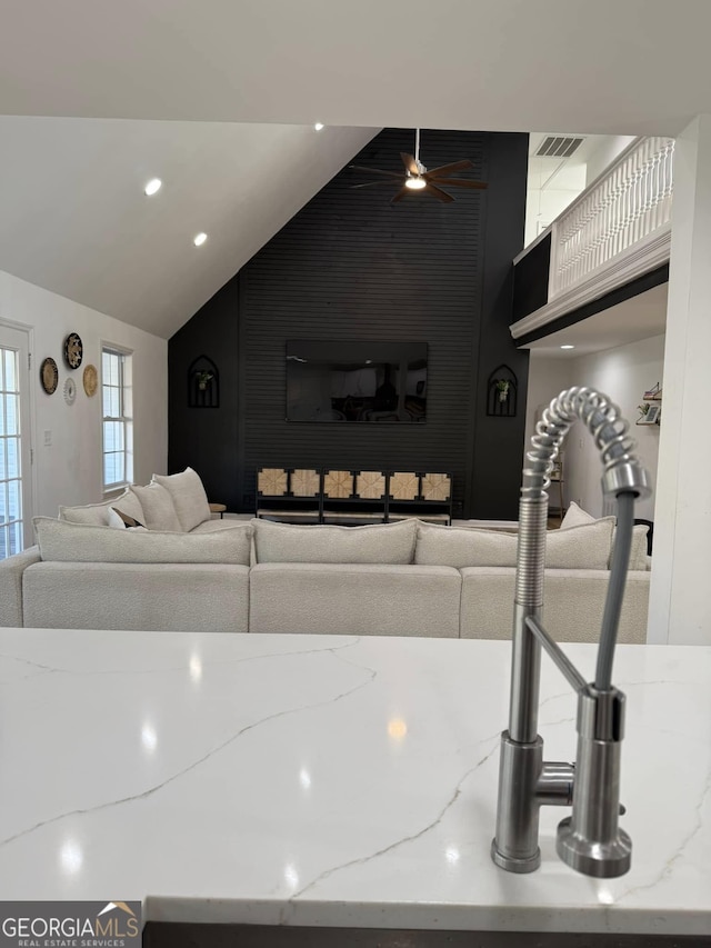 living area featuring lofted ceiling, visible vents, and ceiling fan