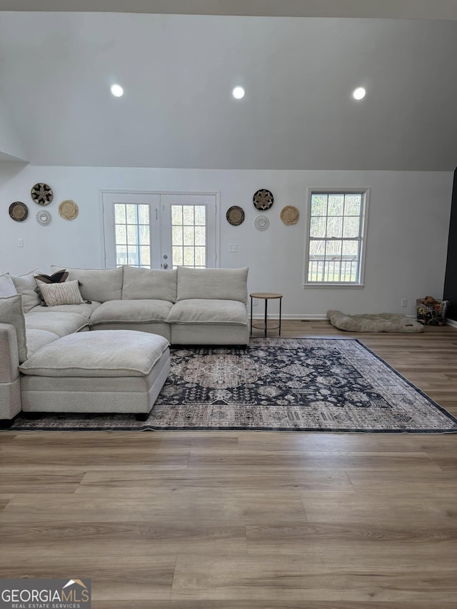 unfurnished living room with vaulted ceiling, a wealth of natural light, and wood finished floors