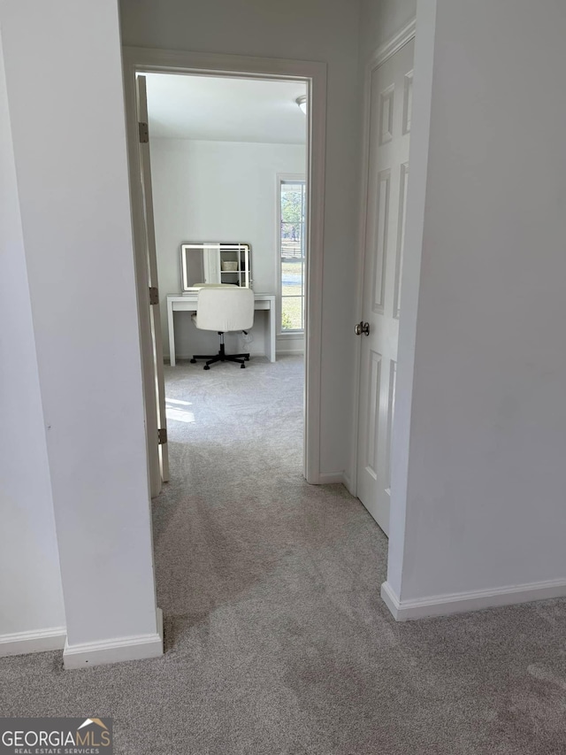 hallway featuring carpet flooring and baseboards