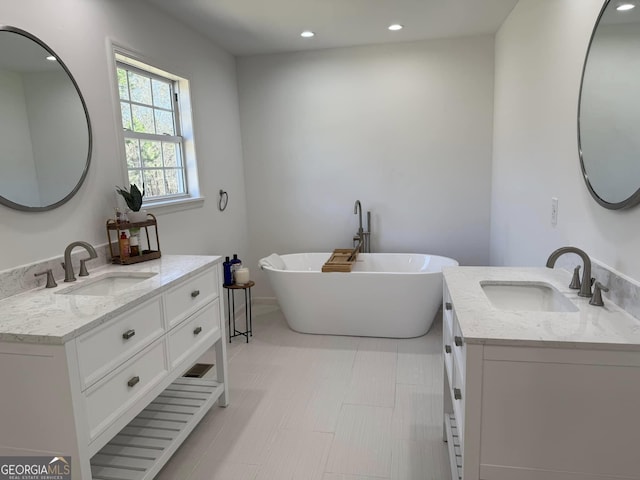 full bathroom featuring a freestanding bath, two vanities, a sink, and recessed lighting