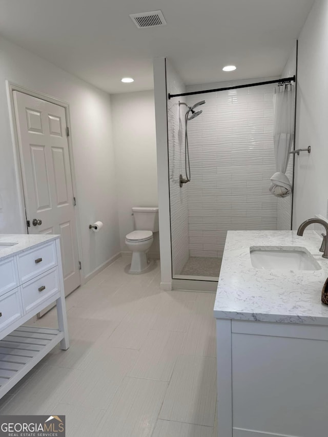 full bath with visible vents, toilet, vanity, tiled shower, and baseboards