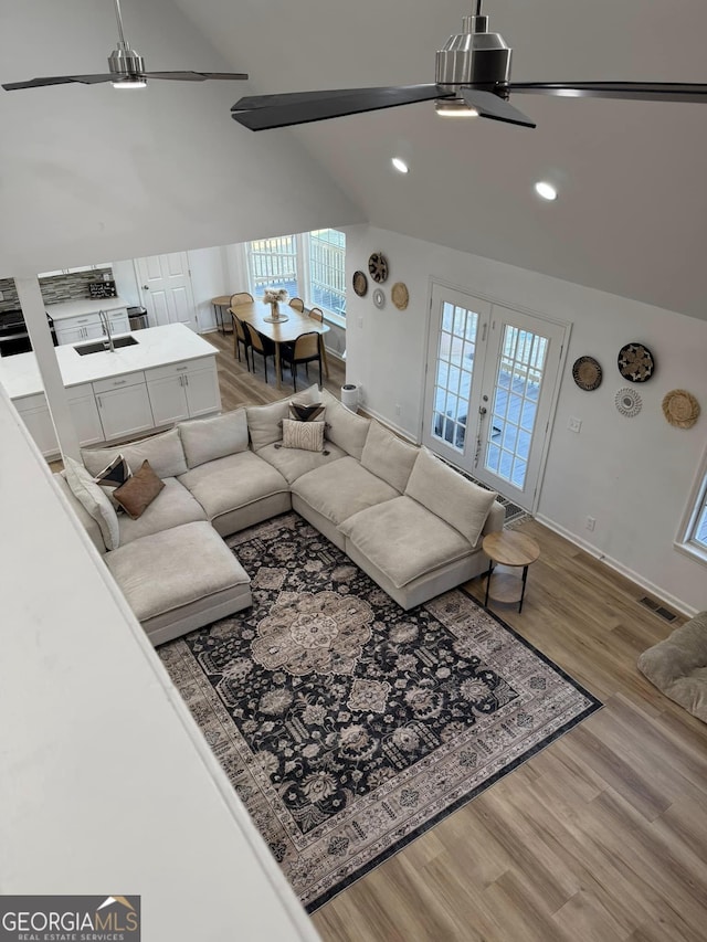 living area with ceiling fan, wood finished floors, lofted ceiling, and visible vents