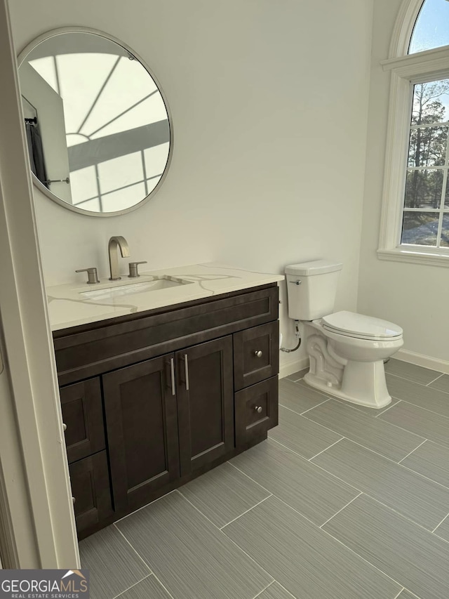 bathroom with vanity, toilet, and baseboards