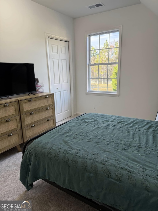 carpeted bedroom with a closet and visible vents