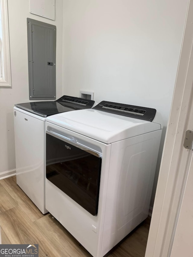 washroom featuring laundry area, light wood finished floors, washing machine and clothes dryer, and electric panel