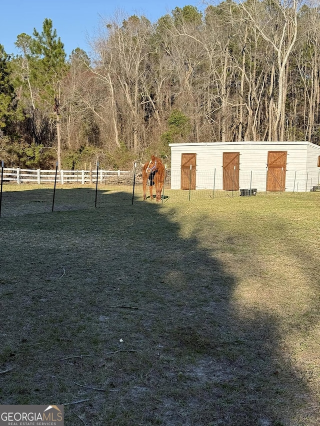 view of yard with a pole building, fence, and an outdoor structure