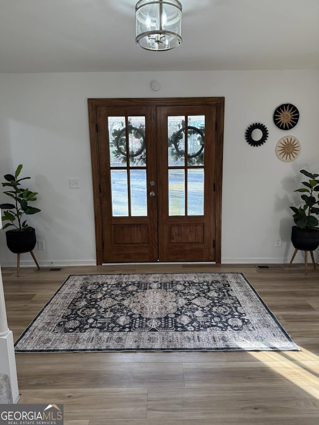 entryway featuring a chandelier, french doors, baseboards, and wood finished floors