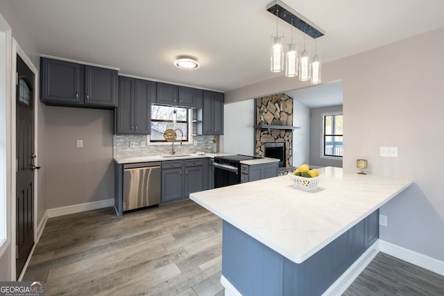 kitchen with backsplash, electric range oven, a sink, dishwasher, and a peninsula