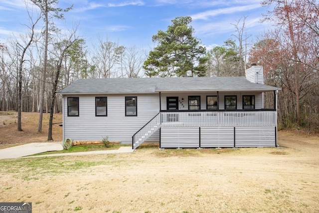 view of front of house with a front lawn, a chimney, stairway, and a porch