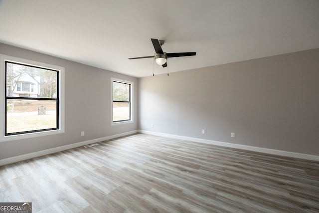 empty room featuring ceiling fan, baseboards, and wood finished floors