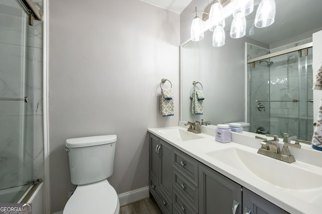 full bath featuring toilet, double vanity, baseboards, and a sink