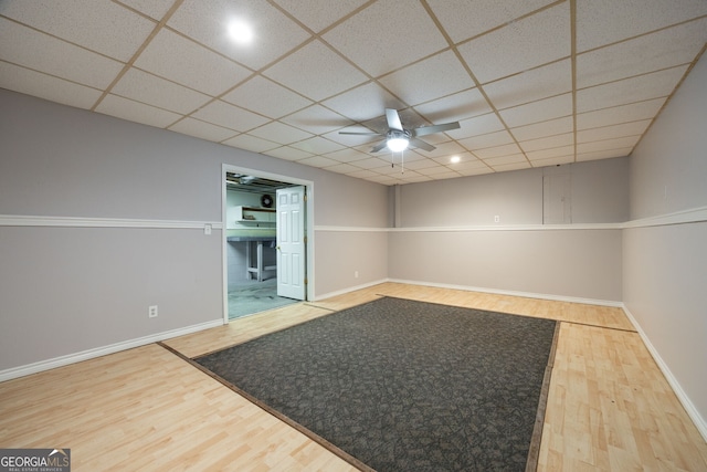 unfurnished room featuring a ceiling fan, baseboards, a drop ceiling, and wood finished floors