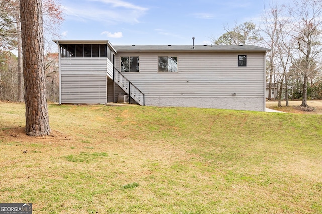 back of property featuring stairs, a yard, and a sunroom