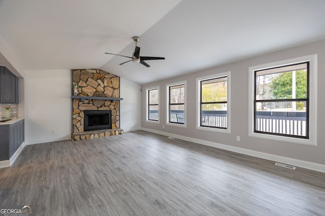 unfurnished living room with lofted ceiling, a fireplace, wood finished floors, visible vents, and baseboards