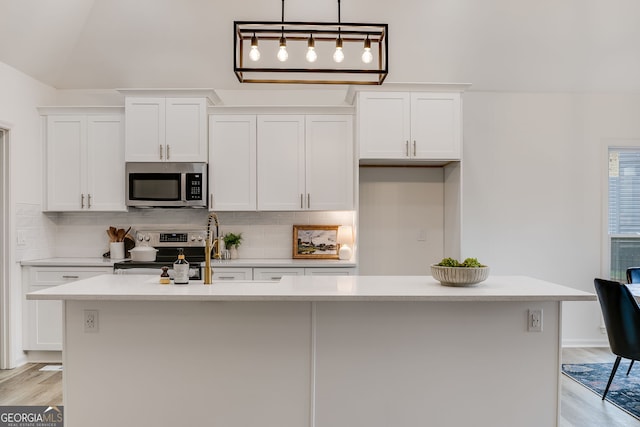 kitchen featuring an island with sink, tasteful backsplash, appliances with stainless steel finishes, and white cabinets