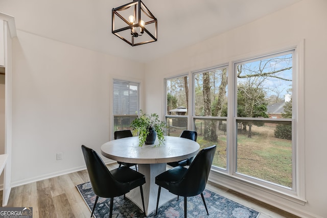 dining area featuring baseboards, light wood finished floors, and an inviting chandelier