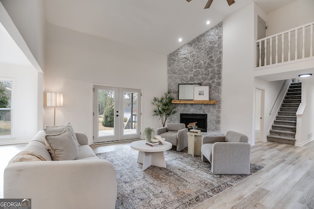 living area featuring stairs, a stone fireplace, plenty of natural light, and wood finished floors