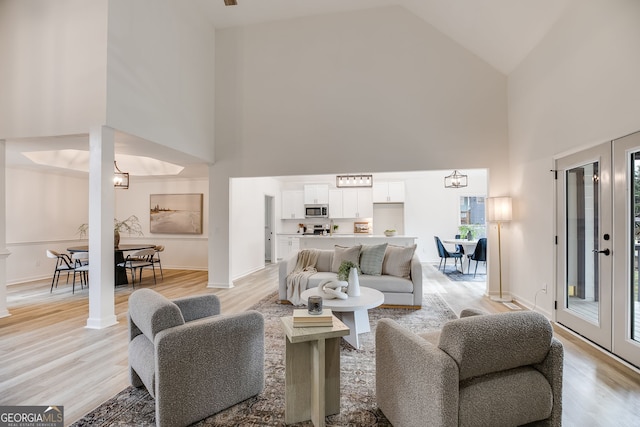 living area featuring high vaulted ceiling, baseboards, and light wood finished floors