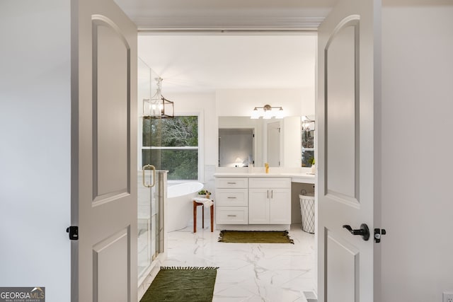 full bath with a stall shower, marble finish floor, a freestanding bath, vanity, and a chandelier