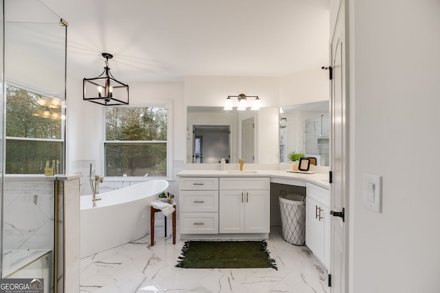 bathroom featuring a chandelier, marble finish floor, a freestanding tub, and vanity