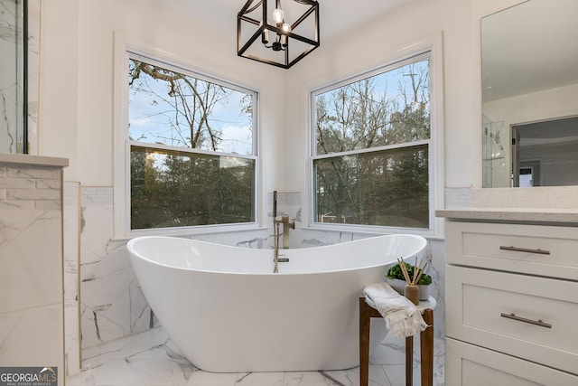 full bathroom with marble finish floor, a freestanding bath, and vanity