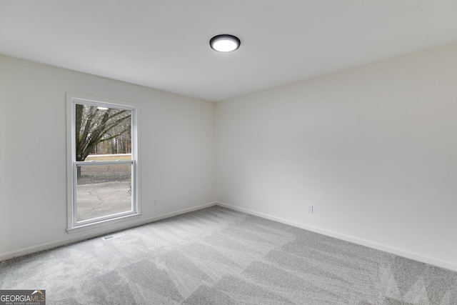 carpeted empty room featuring baseboards and visible vents