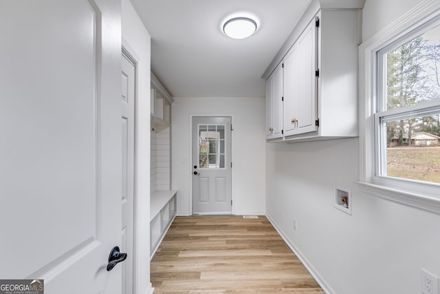 laundry room featuring cabinet space, hookup for a washing machine, baseboards, and light wood-style floors