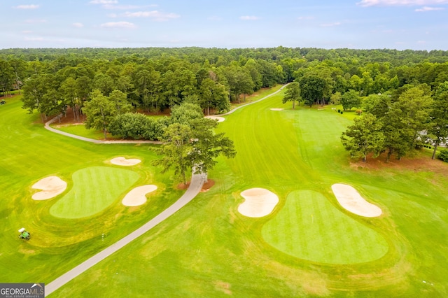 drone / aerial view featuring golf course view and a view of trees