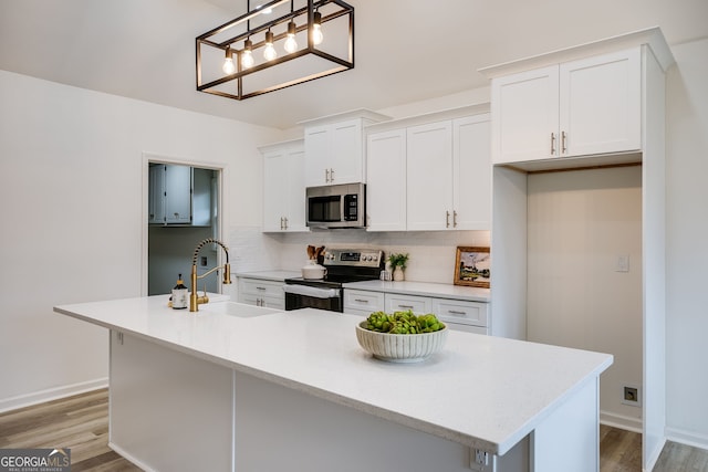 kitchen with light wood finished floors, tasteful backsplash, white cabinets, appliances with stainless steel finishes, and a sink