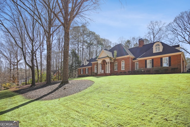 view of front of home featuring a front lawn, brick siding, and a chimney