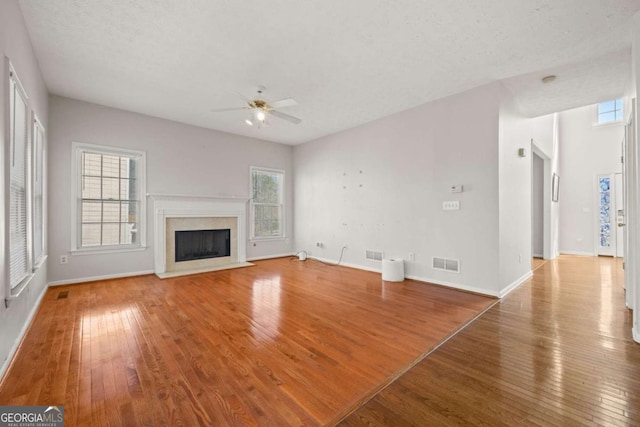 unfurnished living room featuring plenty of natural light, visible vents, a fireplace, and hardwood / wood-style floors
