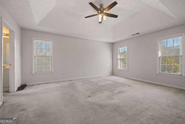 spare room with baseboards, visible vents, a raised ceiling, and carpet flooring