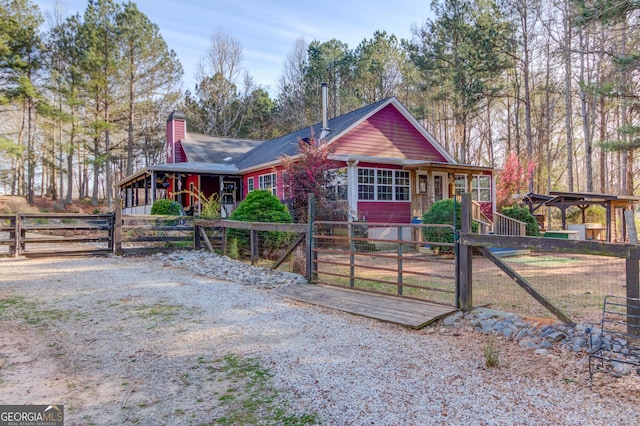 rustic home featuring a chimney, fence, and a gate