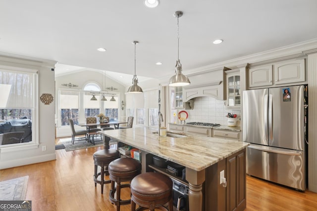 kitchen featuring freestanding refrigerator, light wood-style flooring, glass insert cabinets, custom exhaust hood, and a sink