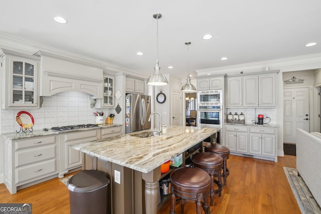 kitchen with a breakfast bar area, glass insert cabinets, a sink, stainless steel appliances, and backsplash