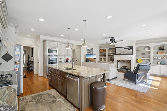 kitchen featuring a sink, stainless steel appliances, a fireplace, crown molding, and a ceiling fan