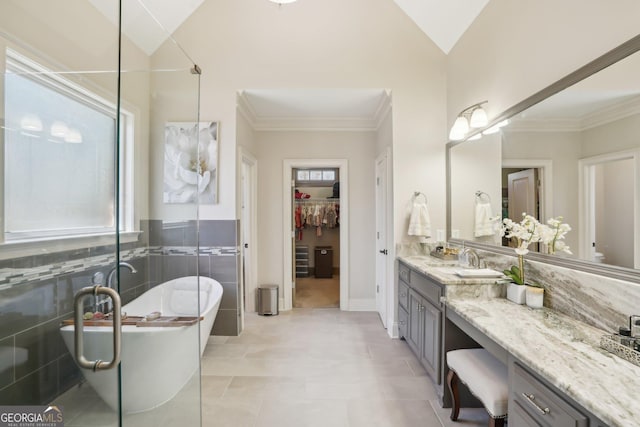 bathroom featuring lofted ceiling, a spacious closet, vanity, and a freestanding tub