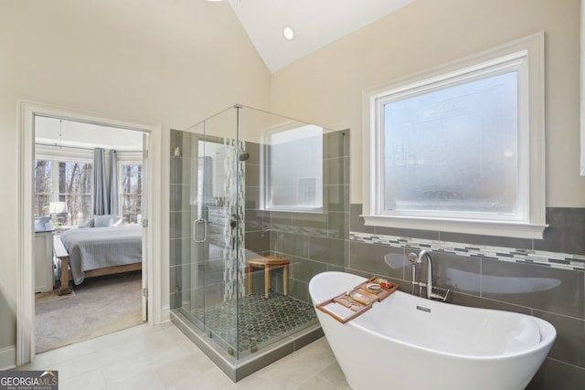 bathroom with a stall shower, tile walls, tile patterned flooring, a freestanding tub, and vaulted ceiling