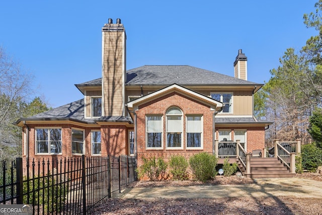 back of house with a chimney, brick siding, stairs, fence private yard, and a deck