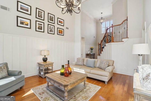 living area featuring a notable chandelier, a decorative wall, visible vents, and stairway