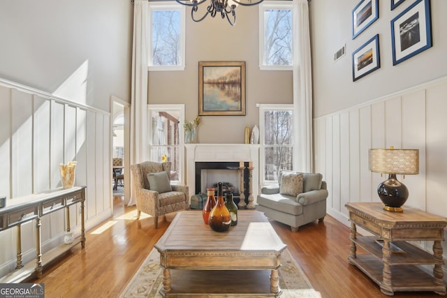 living room featuring visible vents, wood finished floors, a towering ceiling, and a notable chandelier