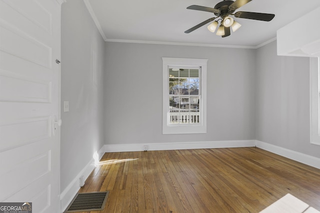 unfurnished room with hardwood / wood-style flooring, baseboards, visible vents, and ornamental molding