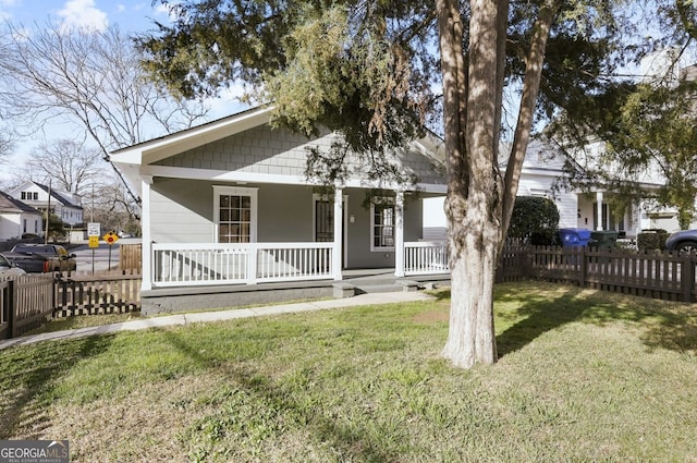 bungalow-style house with covered porch, a front lawn, and fence