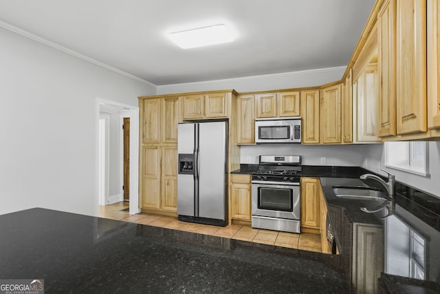 kitchen featuring ornamental molding, light tile patterned floors, dark stone countertops, stainless steel appliances, and a sink