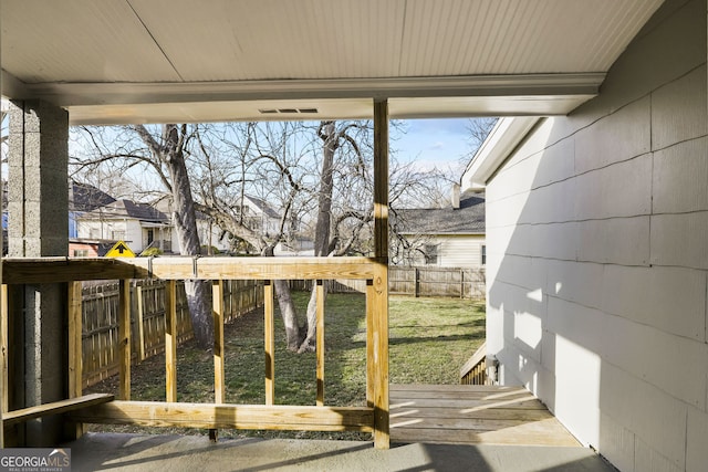 wooden deck with a lawn and a fenced backyard